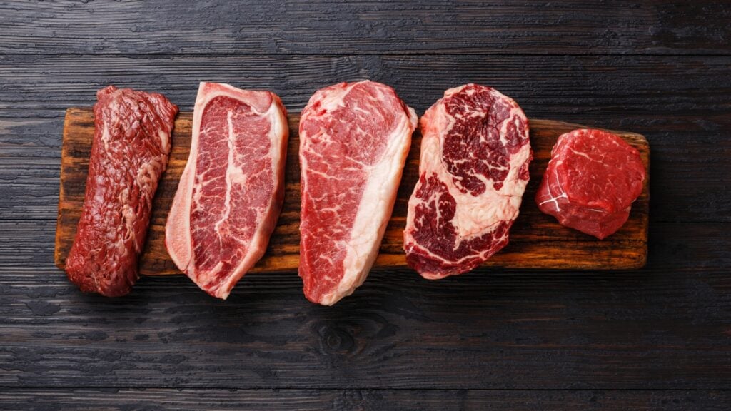 Variety of Raw Black Angus Prime meat steaks Machete, Blade on bone, Striploin, Rib eye, Tenderloin fillet mignon on wooden board copy space